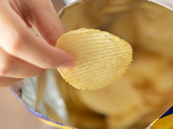 Hand hold potato chips with snack bag